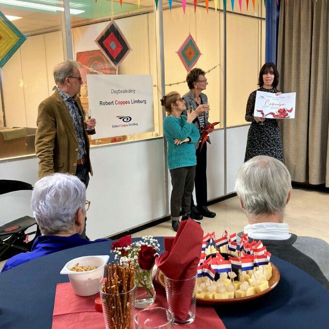 Marian van Heerebeek overhandigt een cadeau cheque aan deelnemers van de dagbesteding Jacqueline en Ineke.